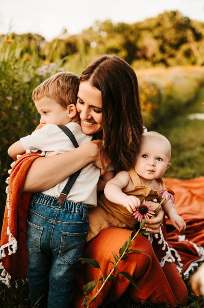 Family Photographer, Mother holds her two children outdoors in the wild